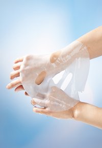 Kostechu hydrating kätemaski, läbipaistev geelmaterjal, ümmargused väljalõiked sõrmede jaoks, kantud kätele nähtava niiskusega, helesinise tausta ees.