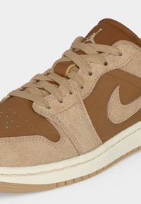 Καφέ και μπεζ Air Jordan αθλητικό παπούτσι με υφές σουέντ και δέρματος, μπεζ κορδόνια, λευκή ενδιάμεση σόλα και ανοιχτό καφέ εξωτερική σόλα.