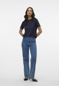 Marinblå t-shirt med kort ärm i kombination med högmidjade, ljusblå denimjeans. Jeansen har en rak benmodell och en klassisk femfickdesign.