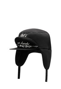 Musta topattu hattu, jossa on etulippa, korvaläpät ja sivulla brodeerattu kuvio, jossa teksti "ed hardy" ja koristeellinen kuvio.