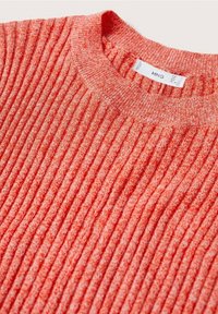 Gros plan sur un pull en maille côtelée de couleur corail orangé avec un col rond et une étiquette de marque MNG visible.