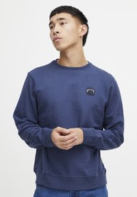 Navy blue sweatshirt in cotton blend, features a round neckline, ribbed cuffs, and a small embroidered logo on the chest.