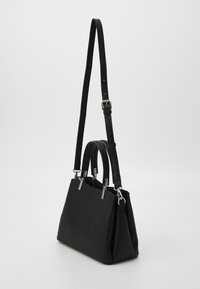 Bolso estructurado negro con asas cortas y una correa para el hombro larga y ajustable, herrajes en plata y cierre superior con cremallera.