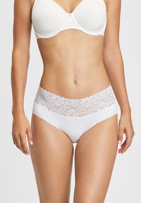 Culotte blanche en coton avec une taille en dentelle florale, présentant une texture lisse et des coutures délicates le long des bords.