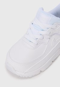 Baskets blanches avec une tige en cuir lisse, une languette en mesh et des accents bleu clair. Elles présentent des lacets ronds et une semelle en caoutchouc texturée.