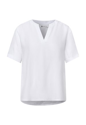 Blouse blanche à manches courtes avec un col en V et un col rond, design simple, et ourlet légèrement arrondi.