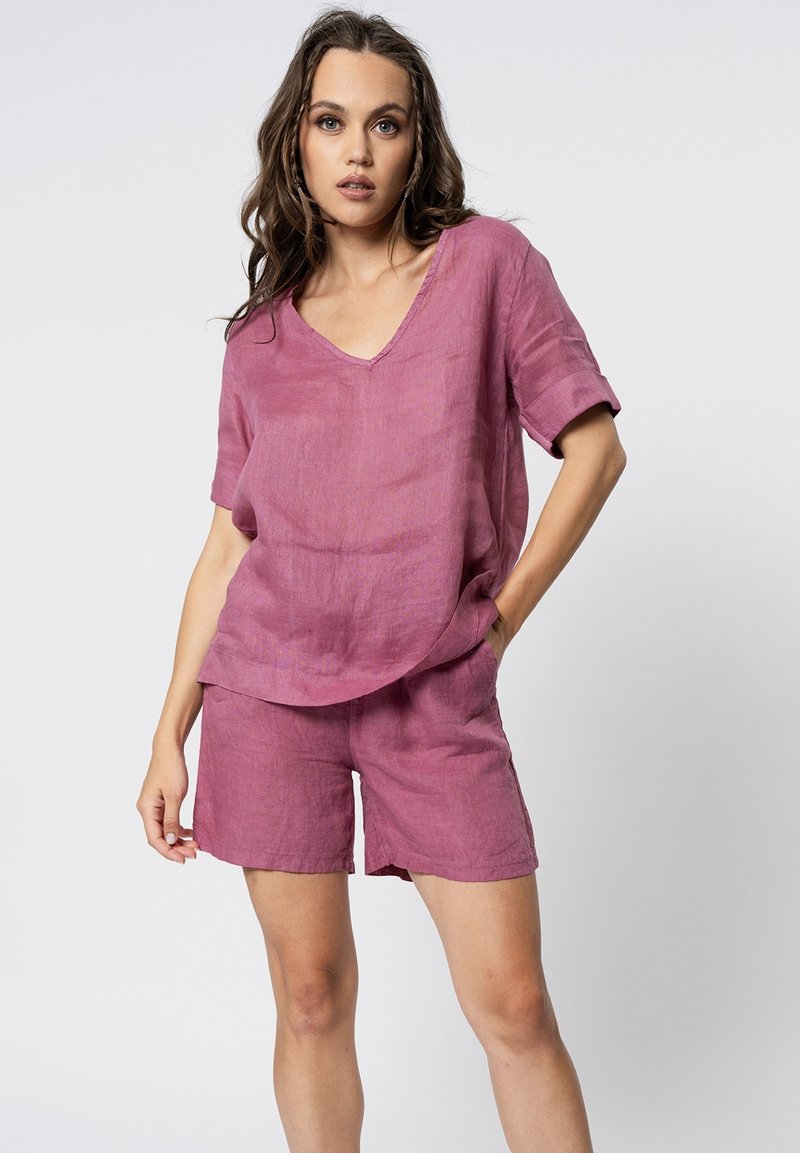 Losse V-hals top en bijpassende shorts in een textuur, lichtgewicht stof. Kleur: gedempt roos. Kenmerken zijn korte mouwen en een ontspannen silhouet.