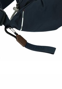 Granatowa torba z teksturowanej tkaniny, z karabinkiem, brązowym skórzanym akcentem i trwałym paskiem z wytłoczonymi literami.