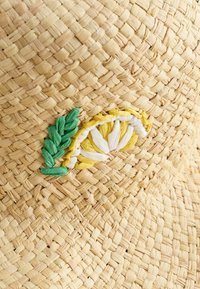 Sombrero de paja con bordados de limón en amarillo y blanco y acentos de hoja verde, presentando una textura trenzada y un color beige natural.