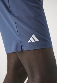 Námořnické sportovní šortky vyrobené z texturované tkaniny, s bílým logem Adidas a bočními rozparky pro snadný pohyb.
