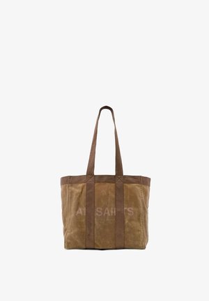 Brun lærredstaske med lange håndtag og forstærkede lodrette stropper, med subtil tekst foran, sat mod en hvid baggrund.