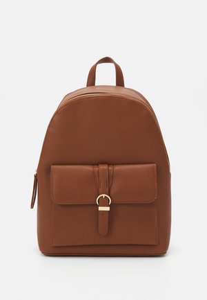 Sac à dos en cuir marron avec poche avant sécurisée par une sangle et une boucle dorée, poignée supérieure et fermeture éclair sur le dessus.