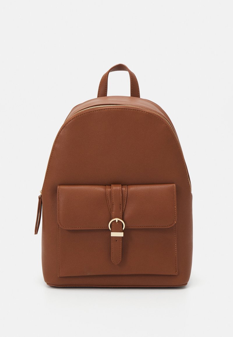 Sac à dos en cuir marron avec poche avant sécurisée par une sangle et une boucle dorée, poignée supérieure et fermeture éclair sur le dessus.