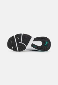 Black and white athletic shoe sole with textured rubber for grip. Features a light blue accent and stylized logo. Patterned tread design.