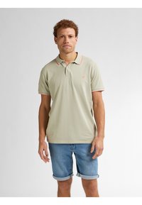 Lichtgroen poloshirt met roze kraagaccent, korte mouwen en logo op de borst, gecombineerd met opgerolde denimshorts. Glad stofgevoel.