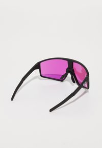 Black sports sunglasses with pink lenses, rectangular shape, textured temple, and a minimalist design, featuring a logo on the side.
