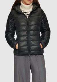 Veste matelassée noire avec capuche, fermeture éclair et poches avant. Présente une texture brillante avec des surpiqûres horizontales et un cordon de serrage réglable.