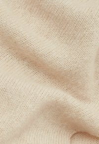 Tejido de punto beige suave con una textura lisa, que presenta un tejido fino y uniforme con sutiles variaciones en tonalidad y patrón.
