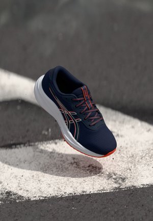 Navy running shoe with mesh upper, white midsole, and red accents. Features a textured surface and visible lacing system.