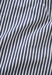 Tissu rayé vertical bleu et blanc avec des plis doux et une légère texture visible en gros plan.