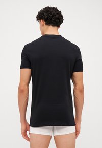 Camiseta negra de manga corta hecha de tejido suave, con un diseño clásico de cuello redondo. No se observan patrones ni acentos destacados.