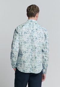 Lange mouw shirt in lichte stof, met een witte basis en groene abstracte bloemmotieven, met een knopen-kraag en aansluitende manchetten.