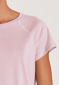 Lichtroze sportshirt met korte mouwen, ronde halslijn en een gladde textuur. Kenmerkt zich door gebogen naden voor een getailleerde look.