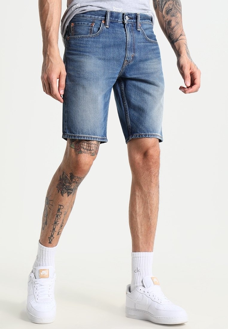 Ljusblå denimshorts med en blekt finish, fem fickor och bälteslatchar. Bärs med vita sneakers och ankelsockor.