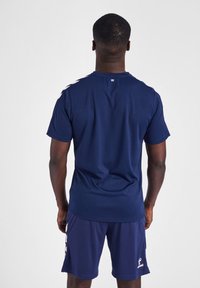 Marineblauw sportshirt met korte mouwen, zachte textuur en een ronde halslijn. Bevat witte strepen op de schouders en een logo op de achterkant.