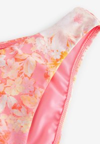Cvečni bikini zgornji del z rožnatimi in oranžnimi odtenki, gladko teksturo in mehkim materialom ter širokim oblikovanjem naramnic.