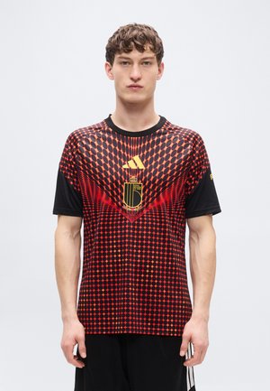 Maillot à manches courtes rouge et noir, présentant un motif à pois, un logo doré et un emblème. Confectionné en tissu léger avec un col rond.