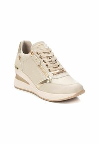 Sneakers beige con design a zeppa, caratterizzati da accenti dorati, un pannello laterale texturizzato e un dettaglio con zip. Materiale liscio con chiusura a lacci.