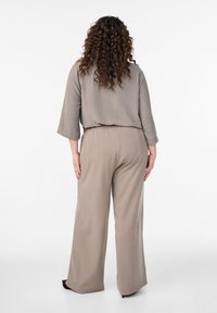 Bež široke hlače z elastnim pasom, kombinirane z ohlapnim sivo zgornjim delom s tremi četrtinami rokavi in teksturirano tkanino.