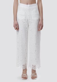 Witte kanten wijde broek met een bloemenpatroon, een soepele tailleband en gegolfde kanten randen. Achterzakken zijn zichtbaar.