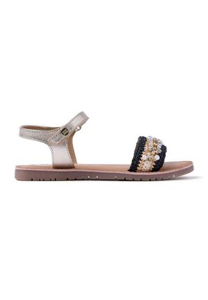 Sandalia de oro metálico con correa ajustable, banda tejida en negro y marrón, cuentas decorativas, suela plana con patrón de tracción sutil.