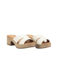 Sandalias de dedo abiertas blancas con un upper texturizado, que presentan un diseño curvado y un tacón de bloque de madera clara. Plantilla marrón visible.