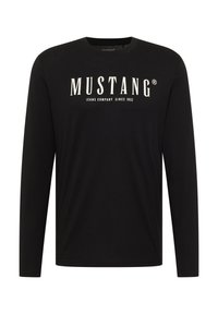 Schwarz langärmeliges T-Shirt aus Baumwolle mit Rundhalsausschnitt, auf der Vorderseite mit dem weißen "MUSTANG"-Logo und dem Text "JEANS COMPANY SINCE 1932" bedruckt.