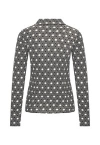 Maglietta a maniche lunghe in bianco e nero, con un motivo decorativo di cerchi e linee radiali. Collo a camicia, silhouette aderente.