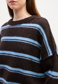 Braun gestreifter Pullover aus weicher Wolle, mit hellblauen und dunkelbraunen Streifen, Rundhalsausschnitt und leicht oversize Passform mit strukturiertem Finish.