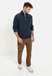 Granatowy sweter z kołnierzykiem na zamek o strukturze, z prążkowanymi mankietami i dołem; w zestawie z brązowymi spodniami z kordurowej tkaniny i białymi sneakersami.