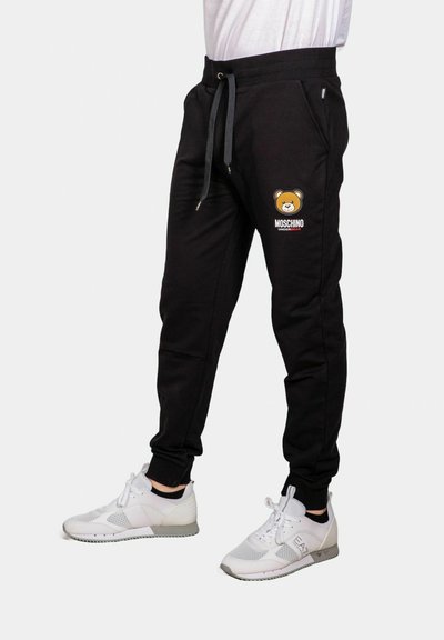 Pantaloni sportivi neri con grafica di un orso e testo "MOSCHINO". Realizzati in morbido tessuto, presentano una vita regolabile e polsini elasticizzati.