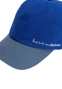 Μπλε και γκρι καπέλο του μπέιζμπολ με ορατές ραφές και κεντημένο κείμενο "Paul Smith loves Barbour" στο μπροστινό μέρος.