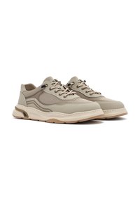 Zapatillas beige con material de malla y sintético, detalles texturizados, cordones redondos y una suela de goma gruesa con franjas de acento.