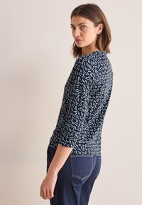 Top a tre quarti con sfondo blu navy e motivi astratti blu chiaro, realizzato in un tessuto morbido e elasticizzato.