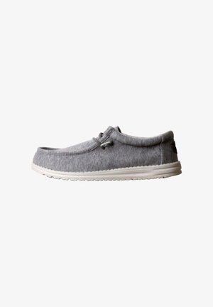 Mocassin décontracté gris avec semelle blanche, dessus en tissu souple et détail de lacet sur le côté, présenté de profil sur fond blanc.