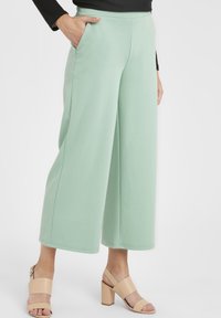 Ljusgröna vida byxor i mjukt tyg med sidofickor. Tillsammans med bruna blockklackade sandaler.