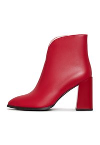 Bottine en cuir rouge avec un bout pointu et un talon rectangulaire épais. Texture lisse avec un détail de couture subtile le long de l'ouverture.