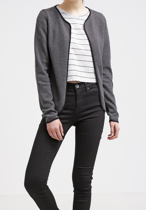 Šedý texturovaný cardigan s kulatým výstřihem a černými detaily, nošený přes bílý pruhovaný top a spárovaný s černými skinny džínami.