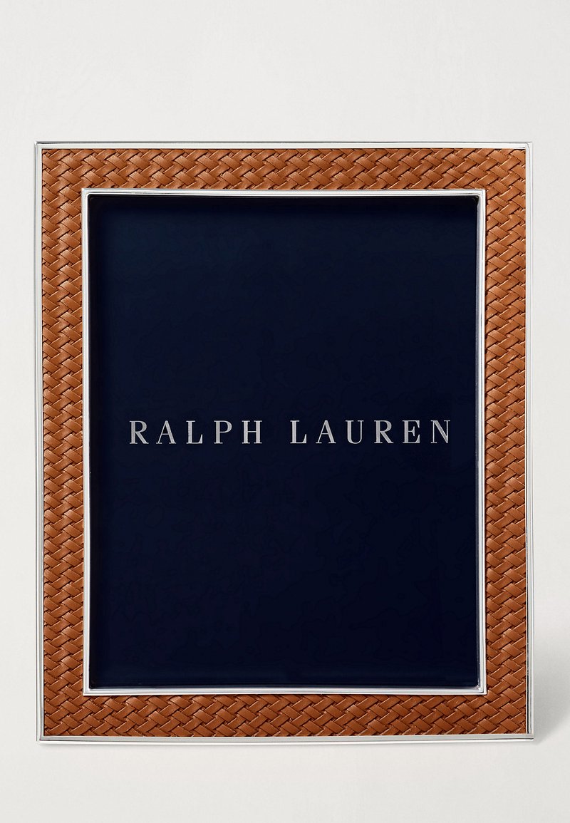 Cadre en cuir tissé brun avec des accents en acier inoxydable et un fond bleu marine arborant le texte "RALPH LAUREN."