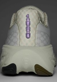 Vaalea harmaa juoksukenkä, jossa on teksturoitu kangaspinta ja jossa on violetti "1080" -merkintä kantapäässä. Pohjassa on mustia, beigen ja oliivin värisiä yksityiskohtia.